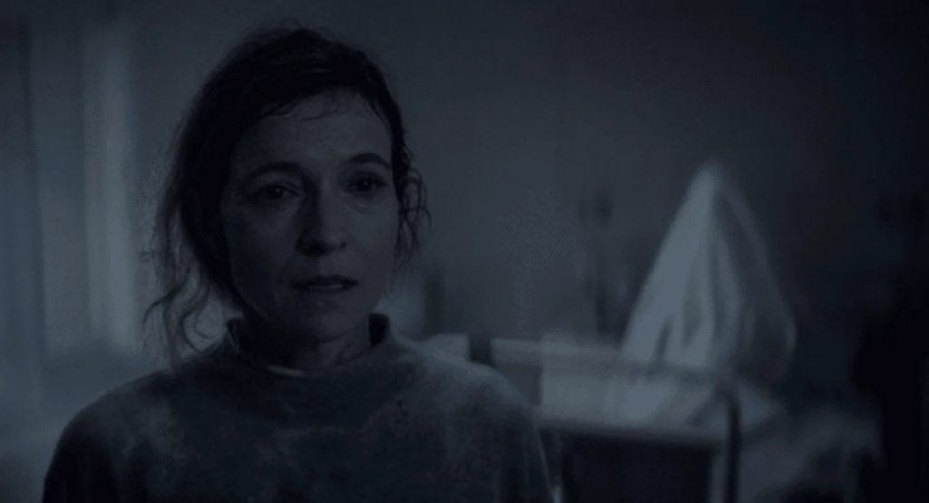 A ghostly figure rises behind Tandi Wright's Susan in Evil Dead Burn